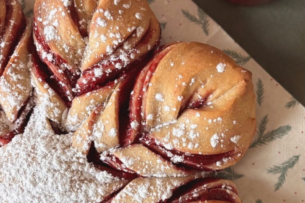 Versgebakken zuurdesem cranberry ster brood ligt op bakkpapier op de tafel naast een pot eigengemaakte cranberry jam