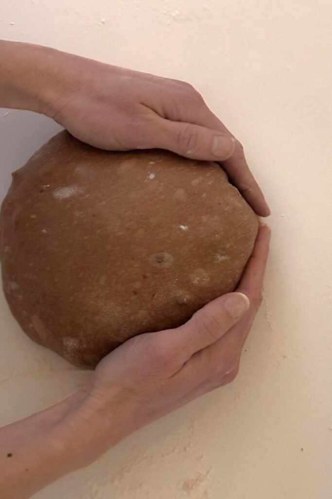 Gerezen chocolade zuurdesem deeg wordt gevouwen op een wit werkblad