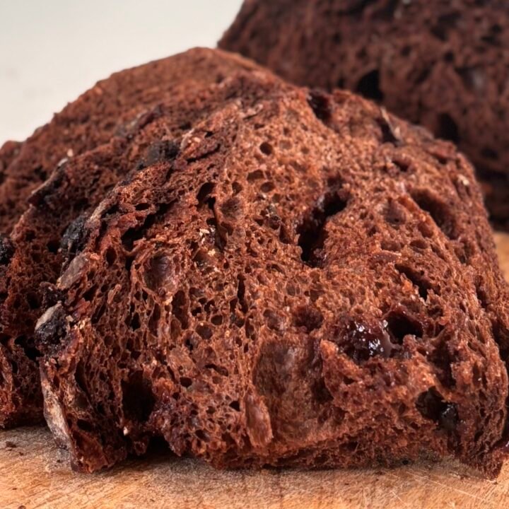 Versgebakken gesneden chocolade zuurdesembrood ligt op een houten plank.