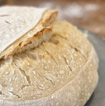 Versgebakken wit zuurdesembrood met mooie insneden ligt op een blauw vintage bord