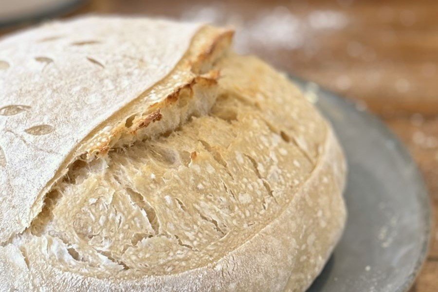 Versgebakken wit zuurdesembrood met mooie insneden ligt op een blauw vintage bord