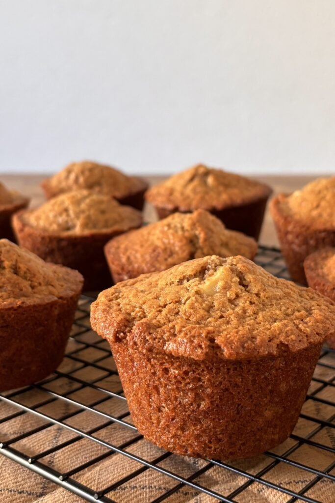 Versgebakken 100% volkoren zuurdesem spelt muffins met appel staan af te koelen op een zwart afkoelrooster