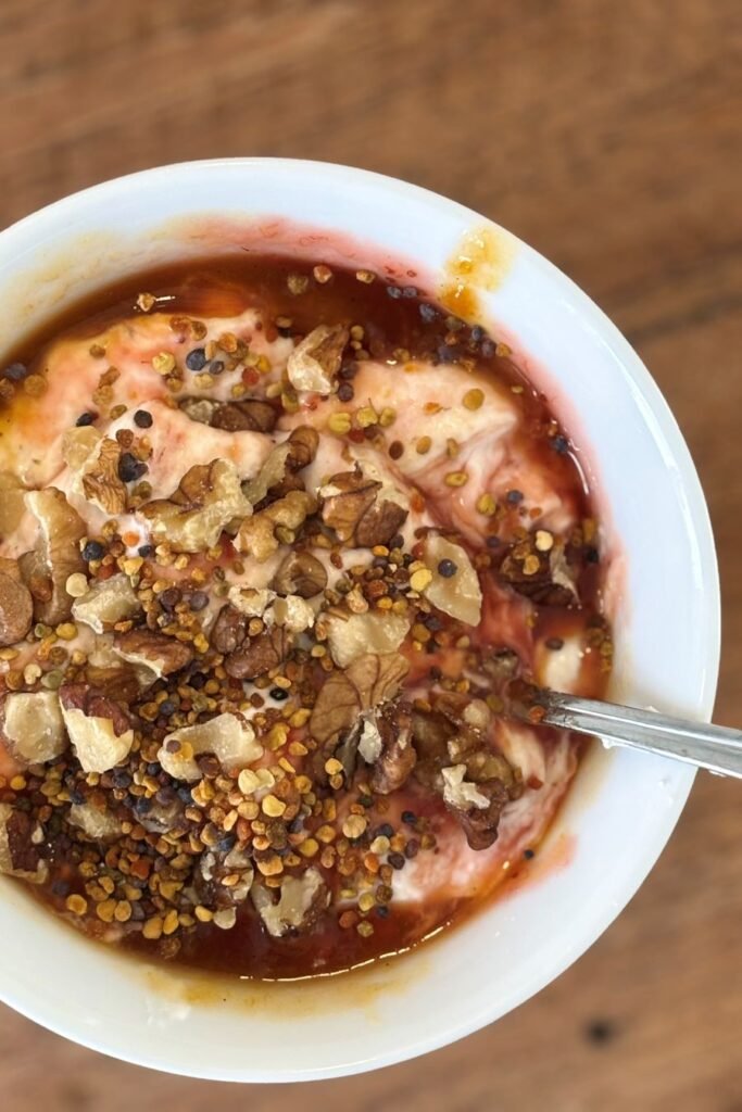Griekse yoghurt met aardbeienjam, walnoten en bijenpollen staat in een kom op tafel