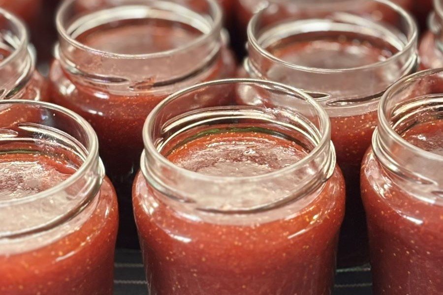 Potten met versgemaakte aardbeienjam staan op een theedoek af te koelen