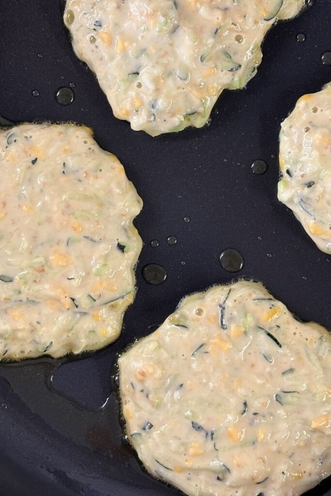Courgette pannekoeken worden gebakken in een koekepan