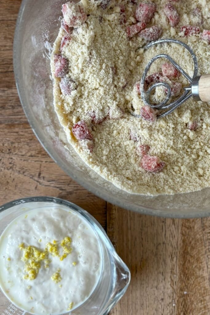 Vrouw maakt scones recept en mengt met een deegklopper de aardbeien door het bloem en boter mengsel