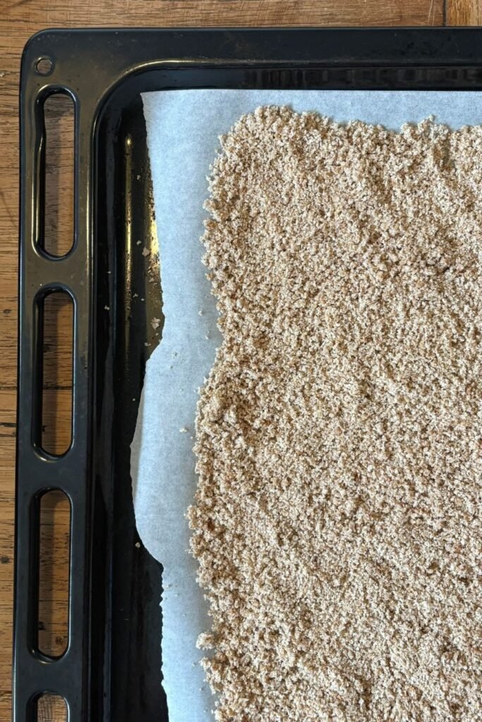 Broodkruimels liggen op bakpapier klaar om de oven in te gaan