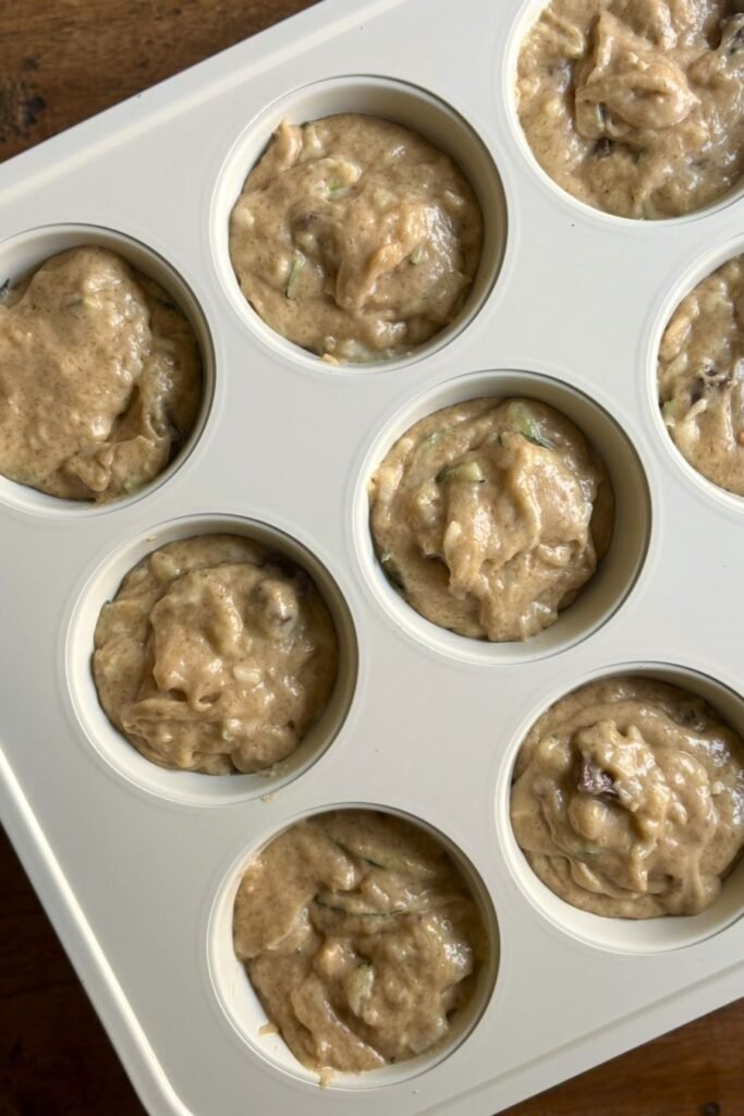 Beslag voor courgette muffins met zuurdesem en chocolate chips ligt in de muffinvorm klaar om afgebakken te worden