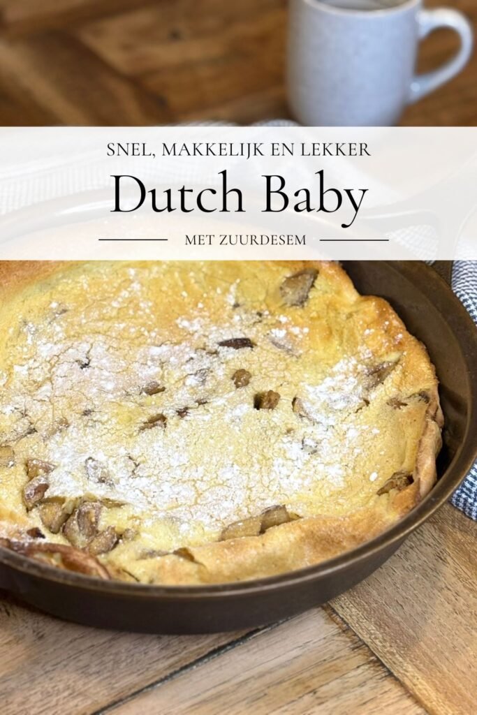 Versgebakken zuurdesem pannenkoek met discard en appel ligt in een gietijzeren pan op een houten eettafel naast een mok. 