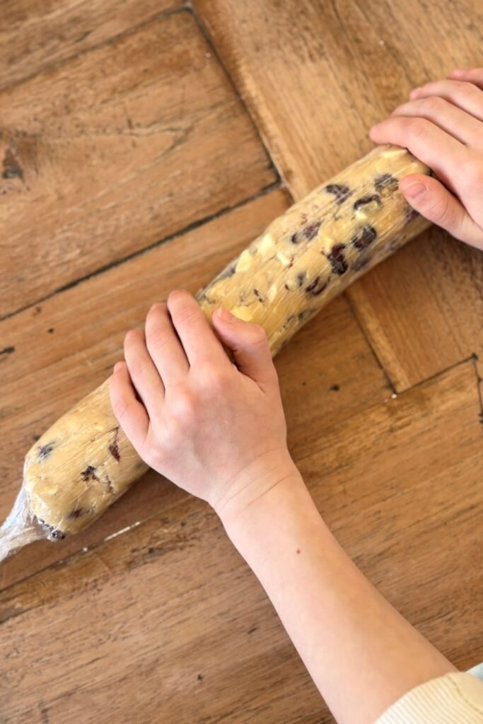 Deeg voor cranberry koeken met witte chocolade wordt in plastic folie gerold.