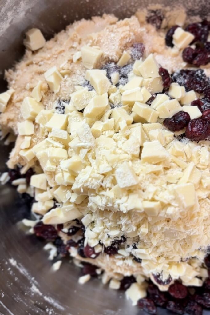 Witte chocolade en cranberries liggen op deeg voor cranberry koeken