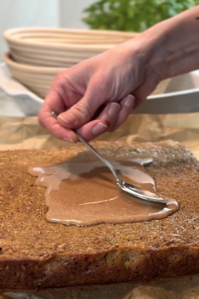 Vrouw smeert cake speculaas in met speculaas icing