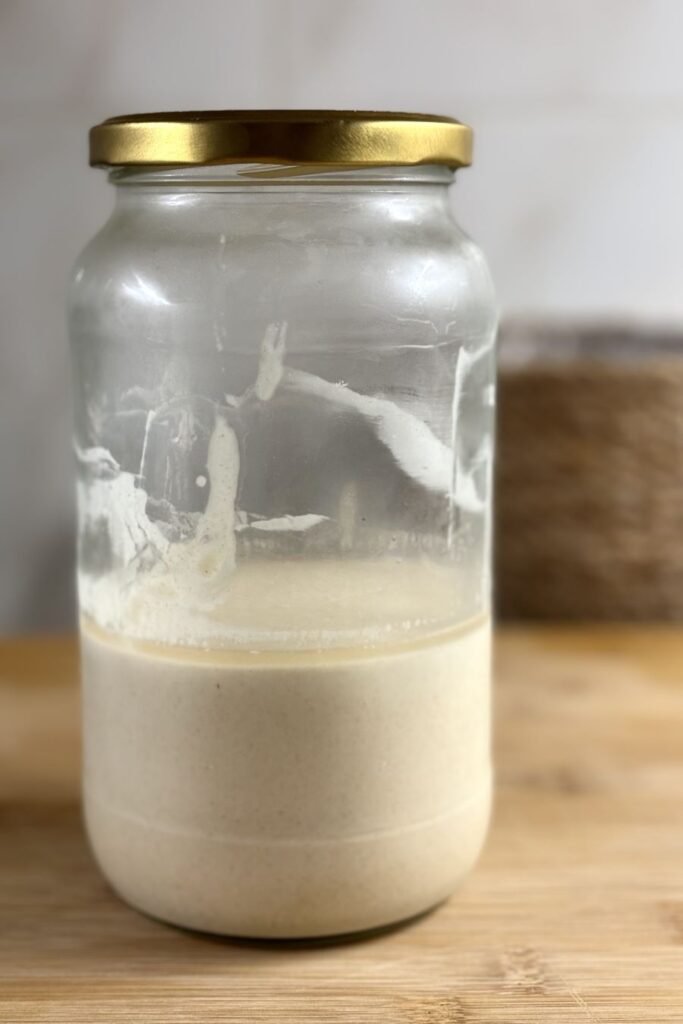 pot met zuurdesem discard met een laagje hooch staat op de eettafel