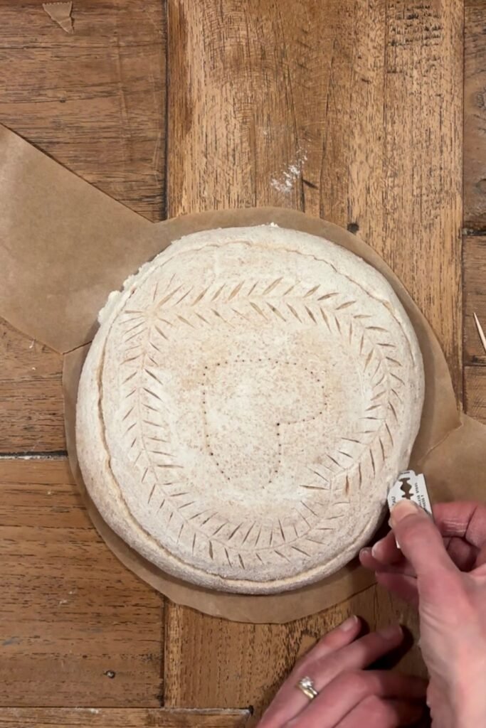 Vrouw maakt diepe snede in zuurdesemdeeg dan kan deeg rijzen in de oven