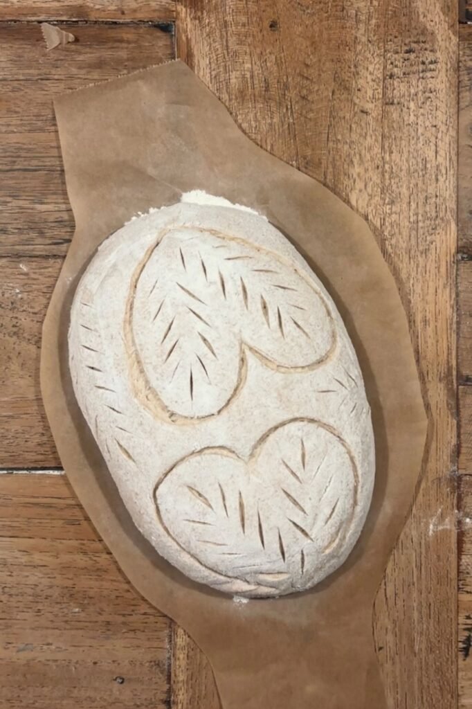 Zuurdesem deeg met mooie hart insneden ligt op een houten eettafel blad