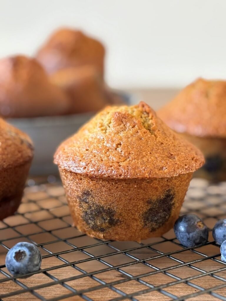 Versgebakken muffins met blauwe bessen staan af te koelen op een rooster