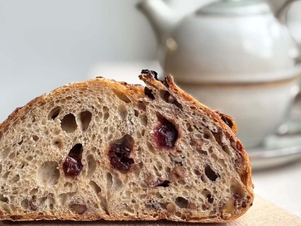 Versgebakken zuurdesem walnoot cranberry brood ligt gesneden op een houten plank
